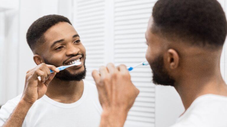 Une main applique du dentifrice sur une brosse à dents avant le brossage