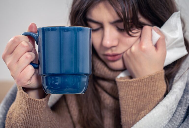 Une personne se couvre chaudement en sortant, bonnet et écharpe bien ajustés pour affronter le froid hivernal