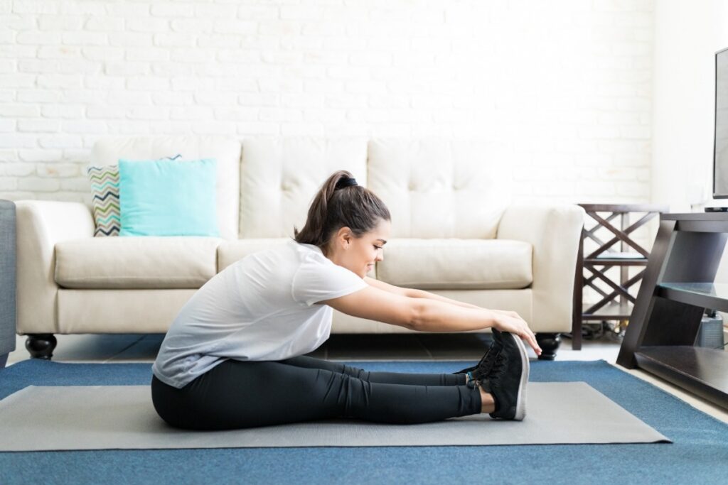 Une femme faisant du stretching dans sa chambre