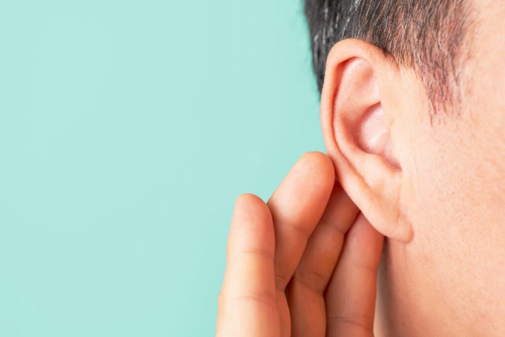 Une personne qui met sa main sur son oreille