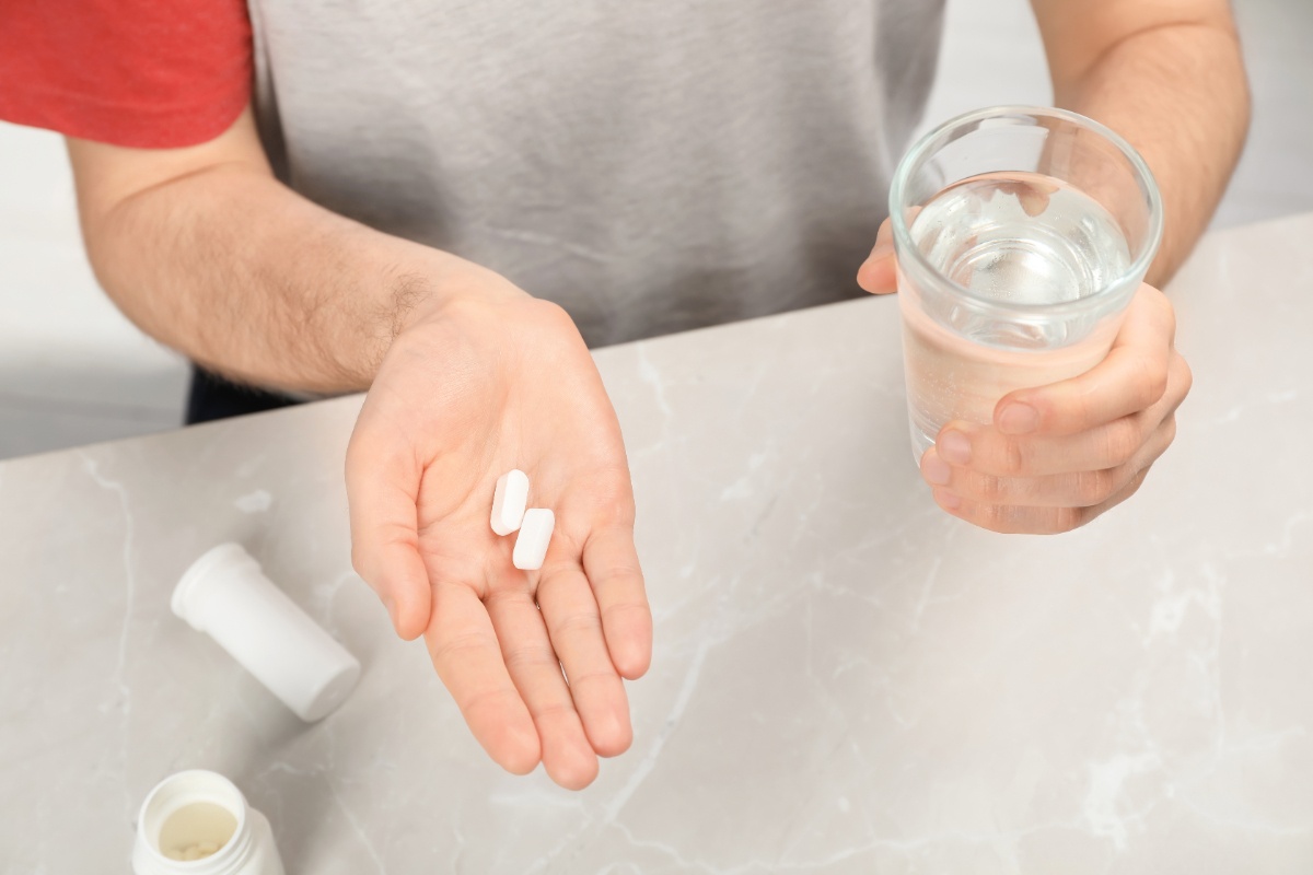 Une personne qui tient un verre d'eau et des médicaments