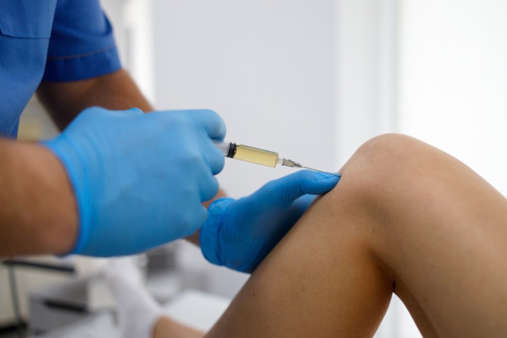 Un médecin faisant une injection sur le genou d'un patient