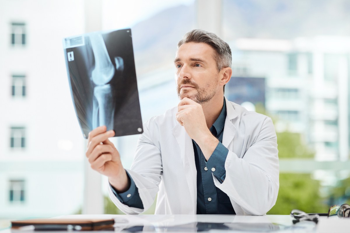Un docteur assis dans son bureau en fixant un résultat d'une radiographie