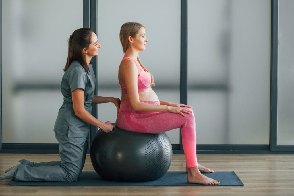 Une femme enceinte faisant un exercice prénatal avec une ostéopathe