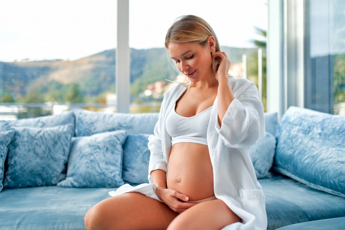 Une femme enceinte heureuse se reposant sur un canapé