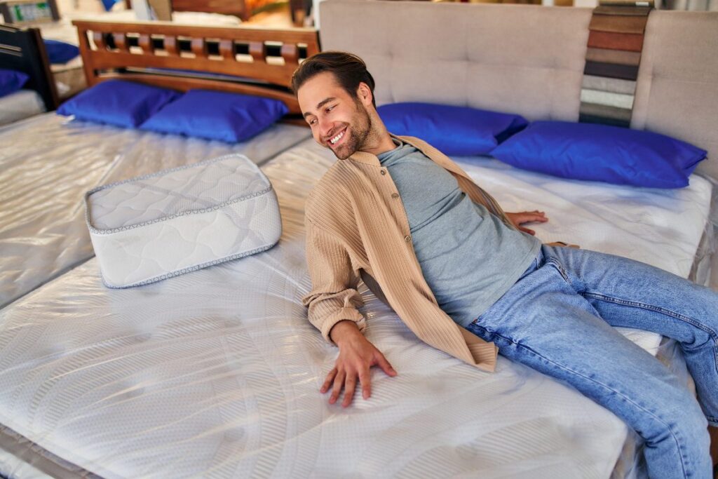 Un homme assis sur un matelas avec des oreillers