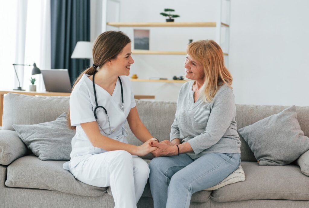 Une infirmière assise sur un canapé et tenant la main d'une femme