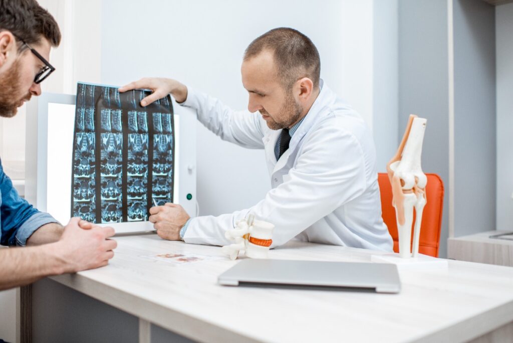 Un médecin qui tient une radiographie et discute avec un patient