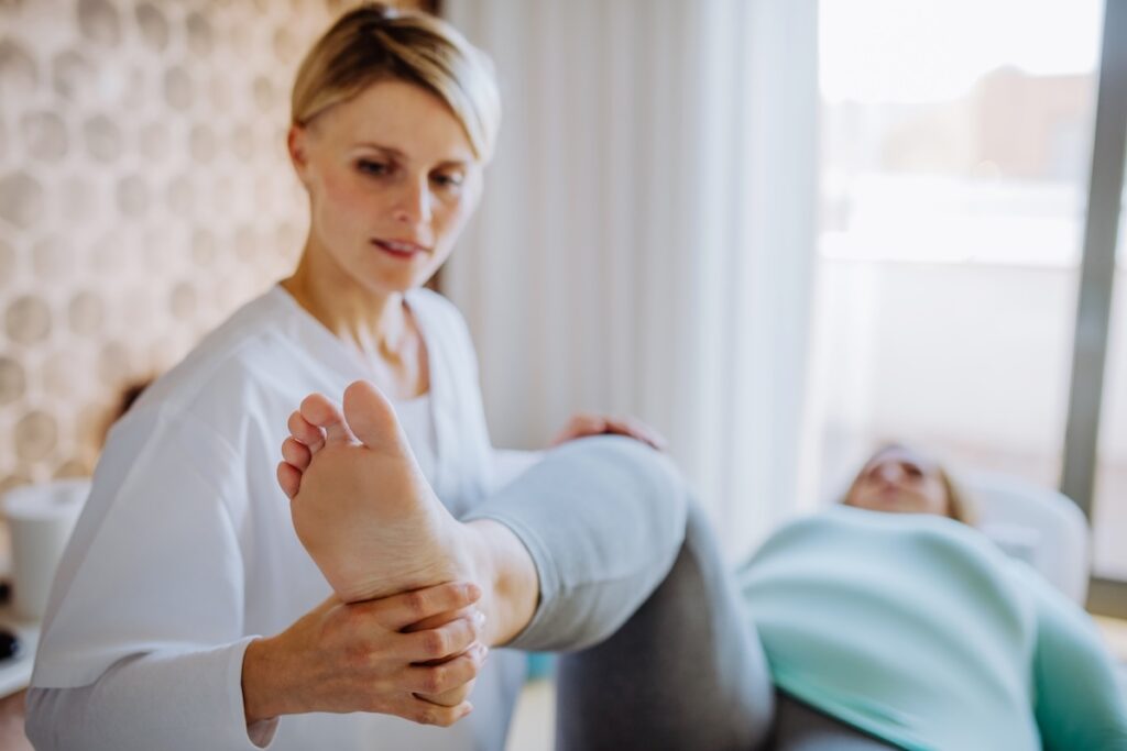 Ostéopathe manipule la jambe d'une patiente